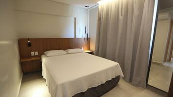 Una habitación de hotel con cama, mesita de noche y espejo.