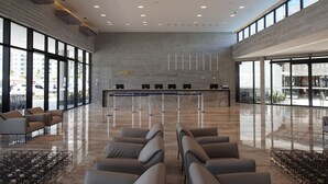 Spaziosa hall con reception, area relax e ampie finestre che offrono vista sull'esterno.
