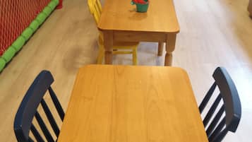 A play area with a slide, a climbing wall, and a table with chairs.