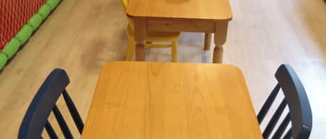 Zona de juegos con tobogán, pared de escalar y una mesa con sillas.