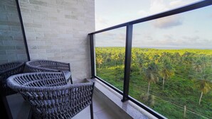 Un balcone con sedie in vimini e vista su un paesaggio verdeggiante con palme.