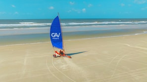 Una playa con un velero solitario, con vela azul y el logotipo 'GV Resorts'.