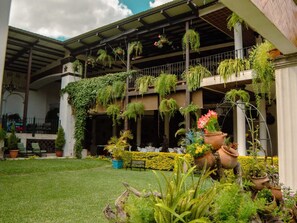 A covered outdoor area with hanging plants, potted plants, and a seating area.