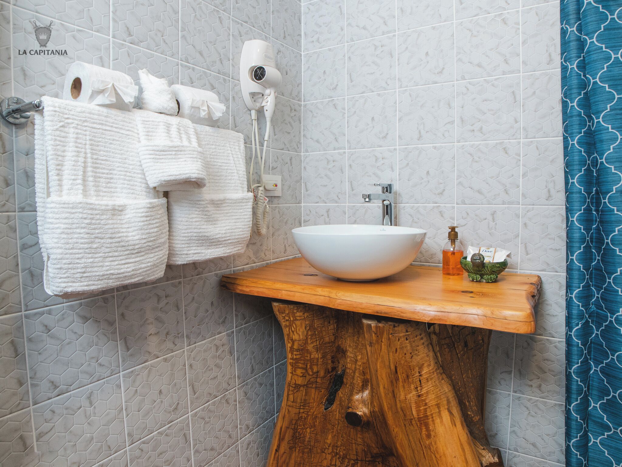 Un baño con tocador de madera, un lavabo blanco y un perchero con toallas.