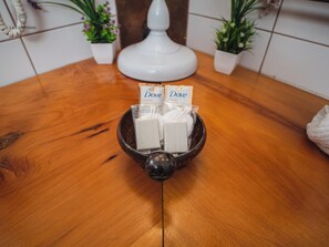 Ein Holztisch mit einer schwarzen Schüssel, in der Taschentücher von Dove liegen, und eine weiße Lampe im Hintergrund.