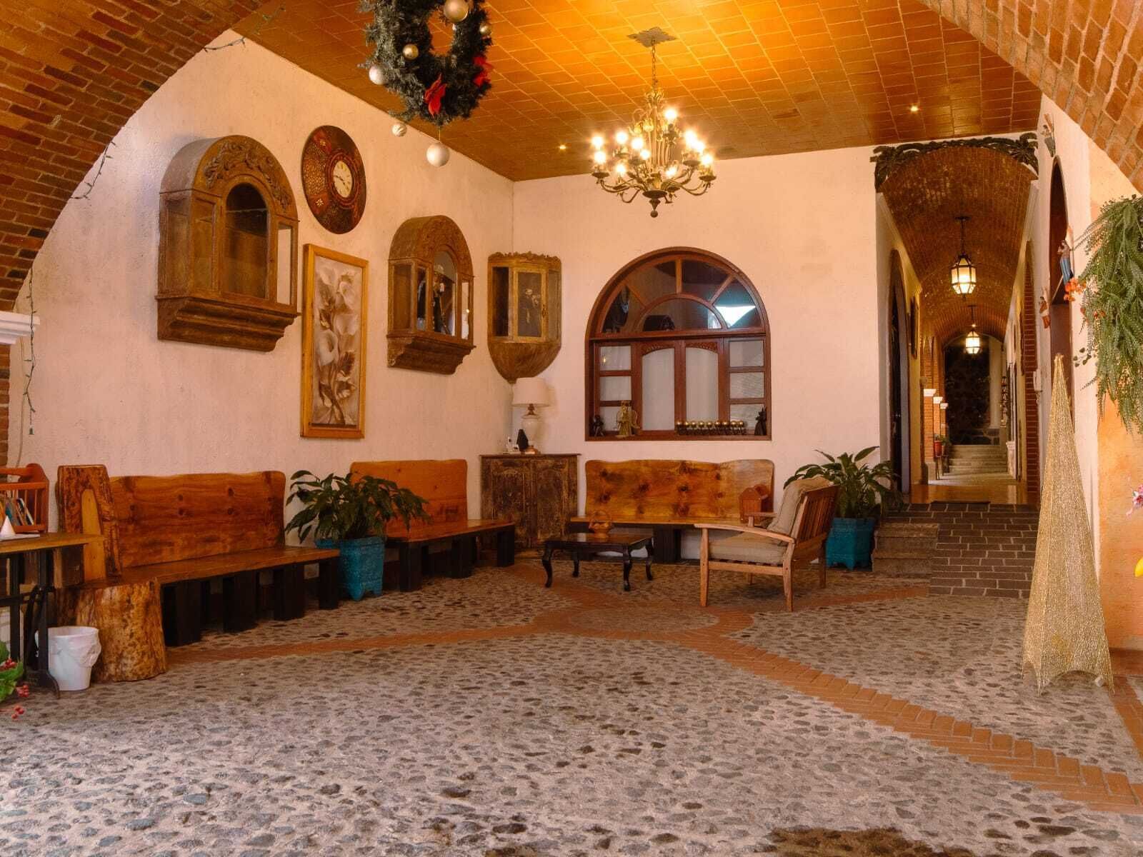 A cozy interior with wooden benches, a chandelier, and a staircase leading to an upper level.