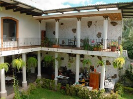 Un espacio al aire libre cubierto, con varios niveles, columnas y plantas en macetas.