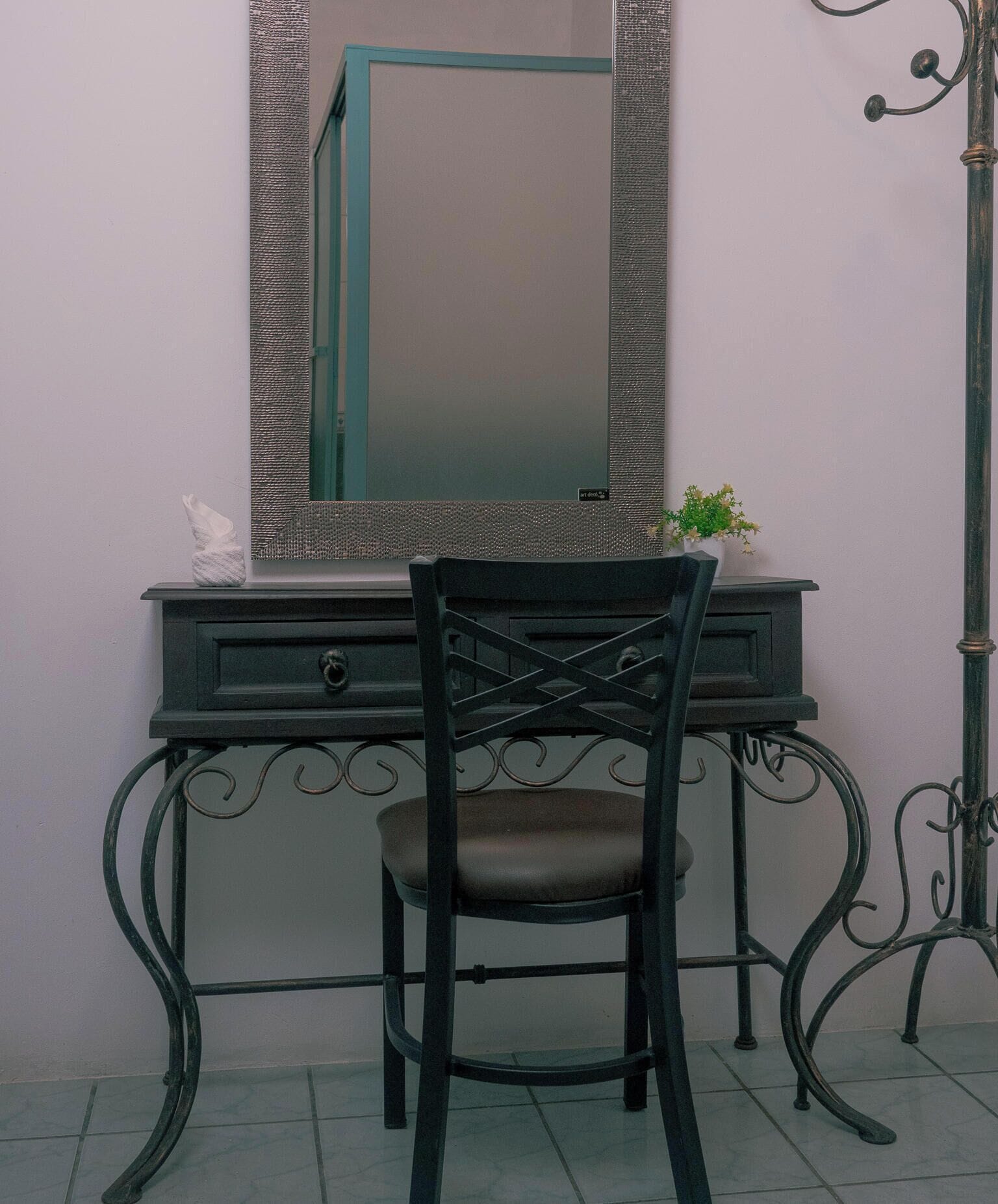 A desk with a mirror, a chair, and a plant.