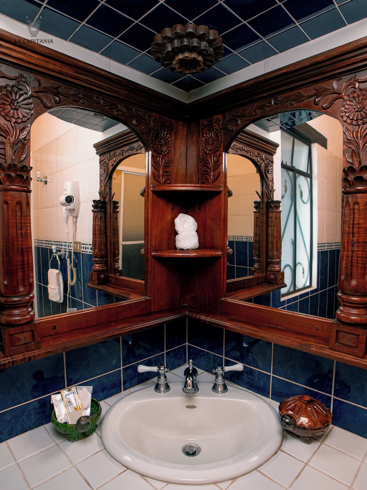 A bathroom with a large mirror, wooden vanity, and a sink.