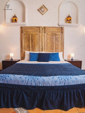 A bed with a wooden headboard, two bedside tables, and a decorative wall piece.