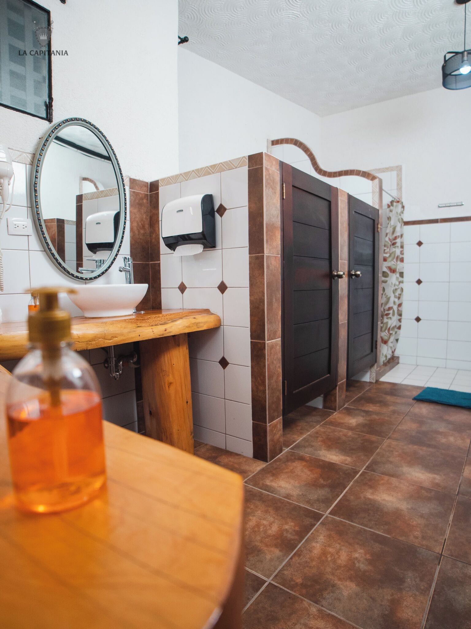 Une salle de bain avec un meuble-lavabo en bois, un évier, un miroir, un distributeur de savon et un porte-serviettes.