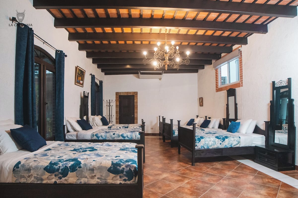 A hotel room with four beds, a chandelier, and a tiled floor.