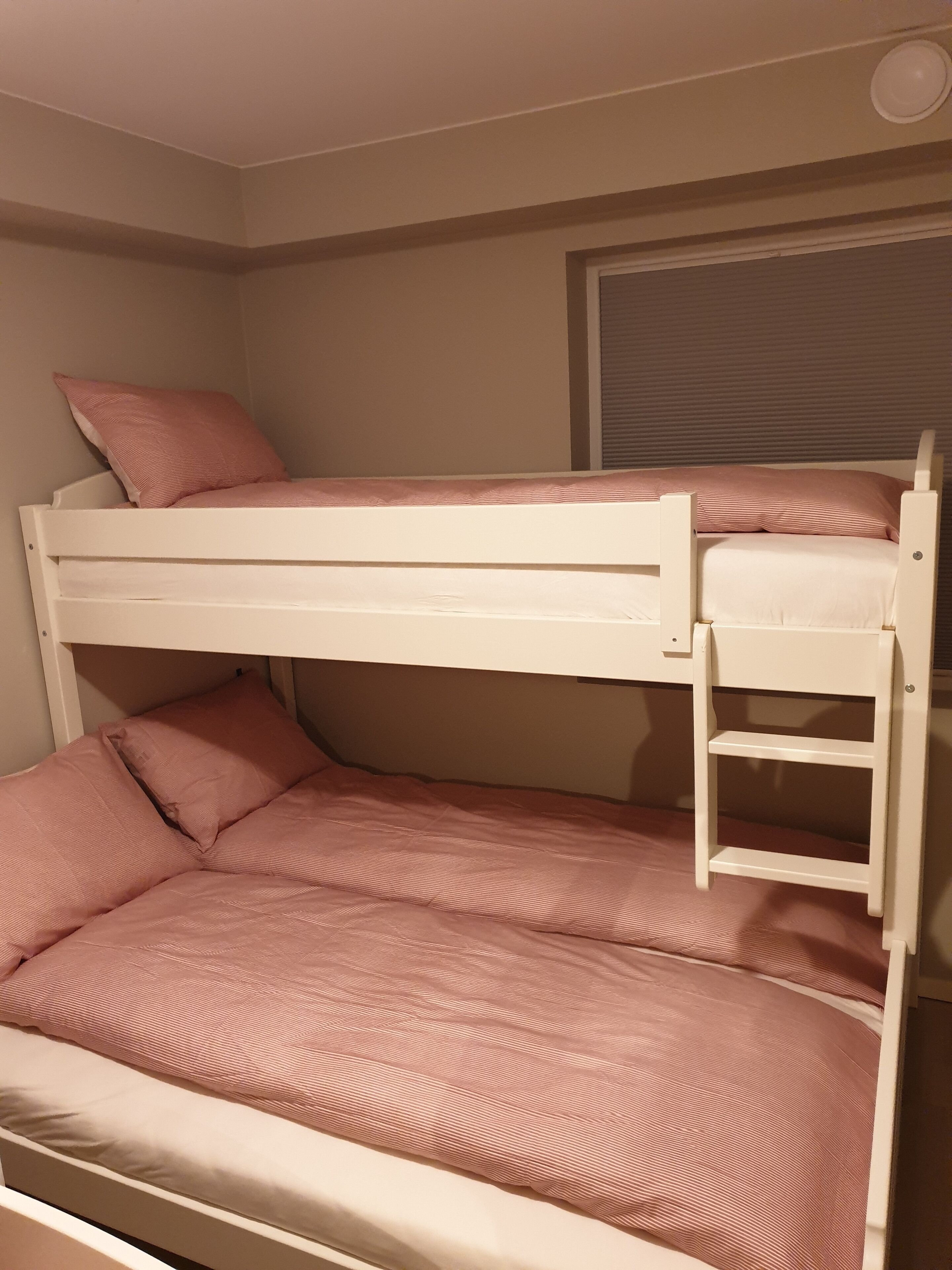 Una cama litera con dos niveles, cada uno con un colchón y almohadas.
