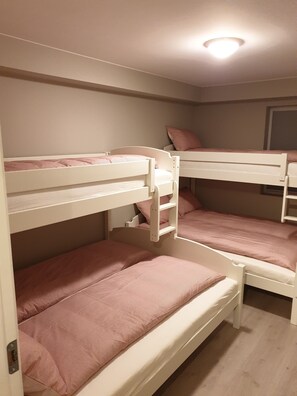 Habitación con literas, dos camas, cada una con ropa de cama rosa.