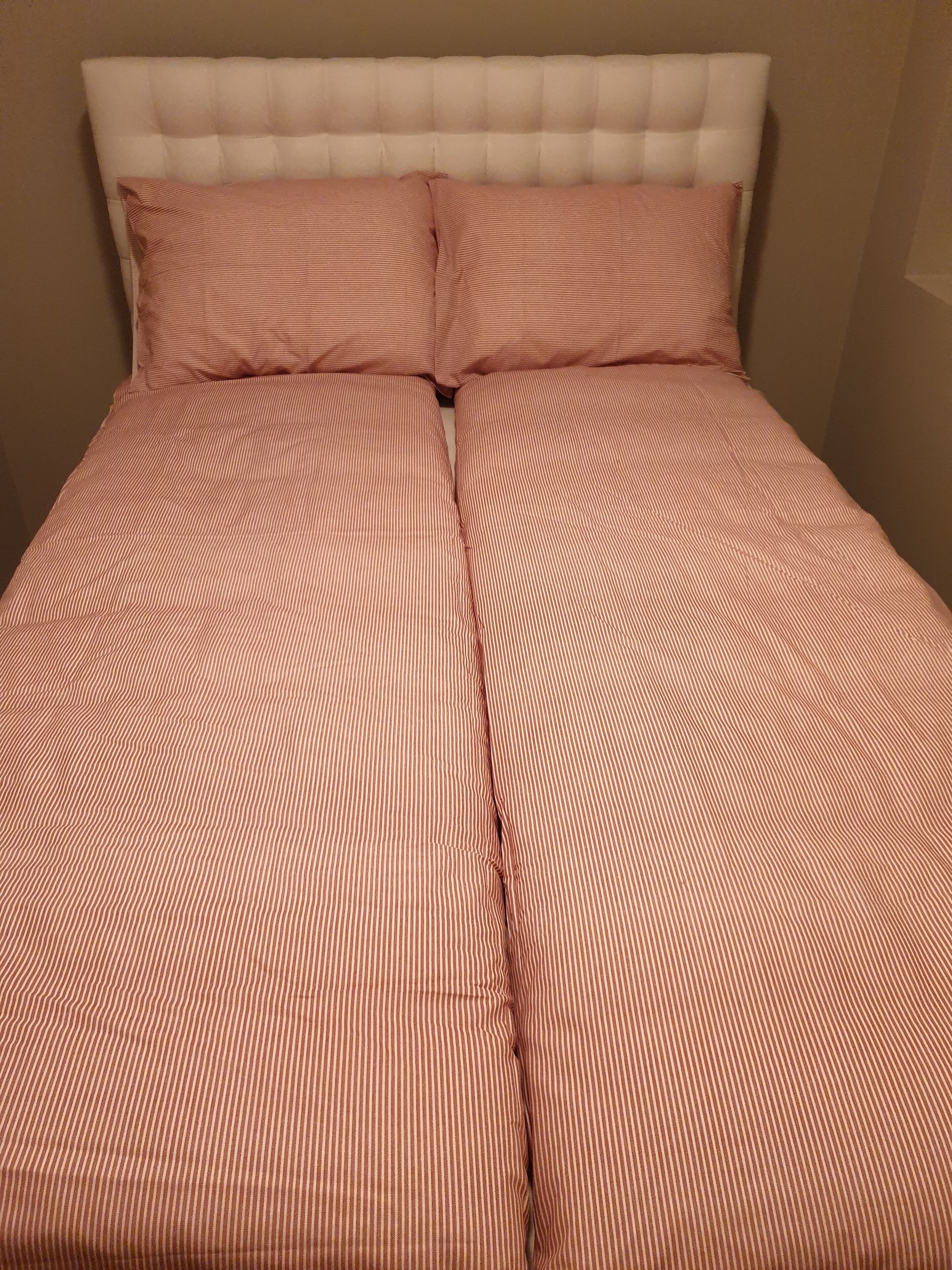 A bed with a striped bedspread and a tufted headboard.