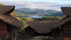 A thatched-roof structure with a view of a lake and mountains in the background. - Sachakuna Resort (Sauce)