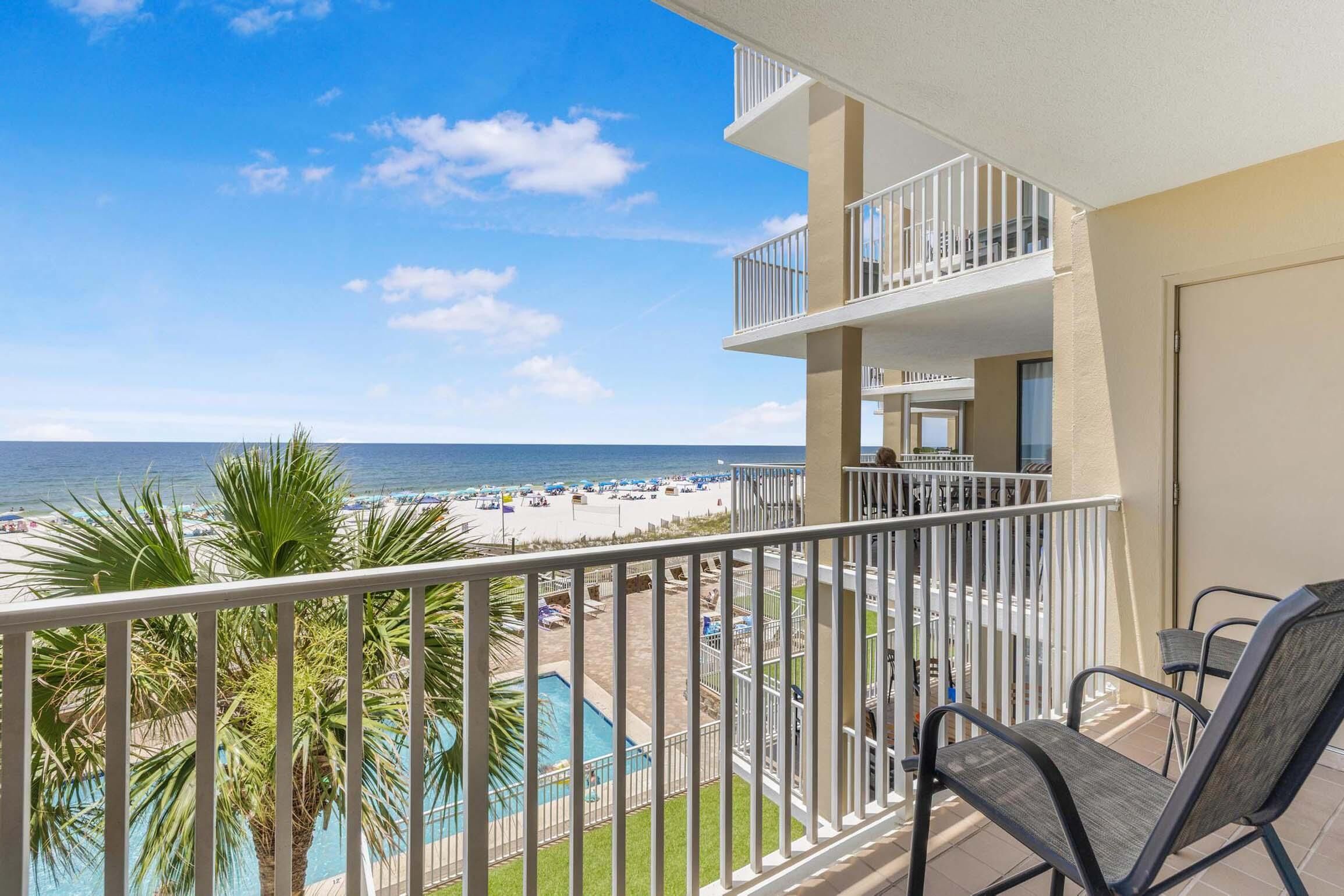 A balcony with a view of a beach and pool.