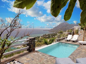 A pool area with lounge chairs and a view of the sea and mountains. - Pyrgos Plakias Villas (Agios Vasileios)