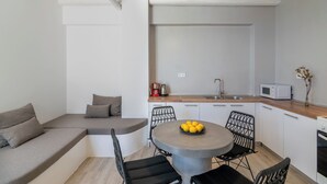 A modern kitchen with a dining area, including a round table with chairs, a built-in bench, and a ceiling fan. - Pyrgos Exclusive Villas (Agios Vasileios)
