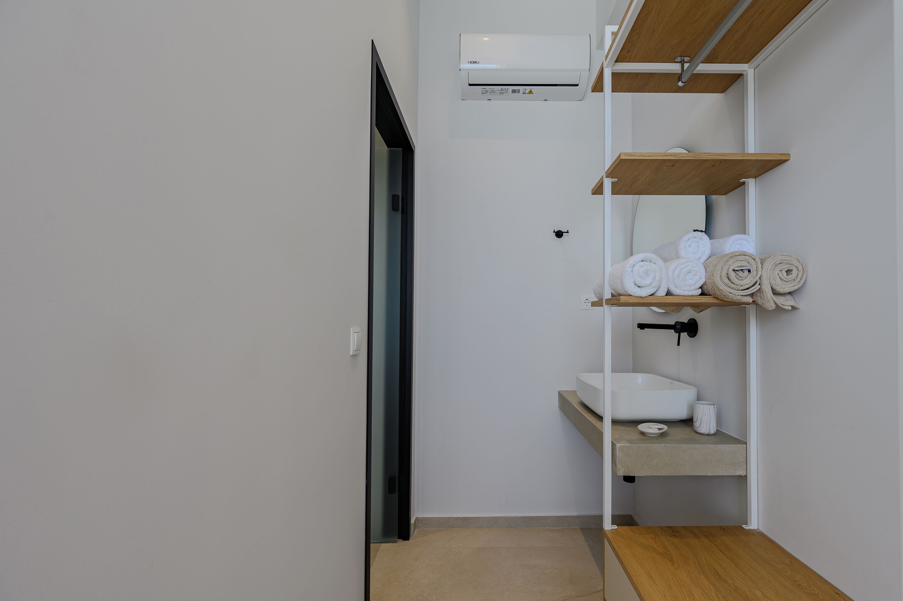 Un baño moderno con lavamanos empotrado, un espejo y un perchero para toallas.