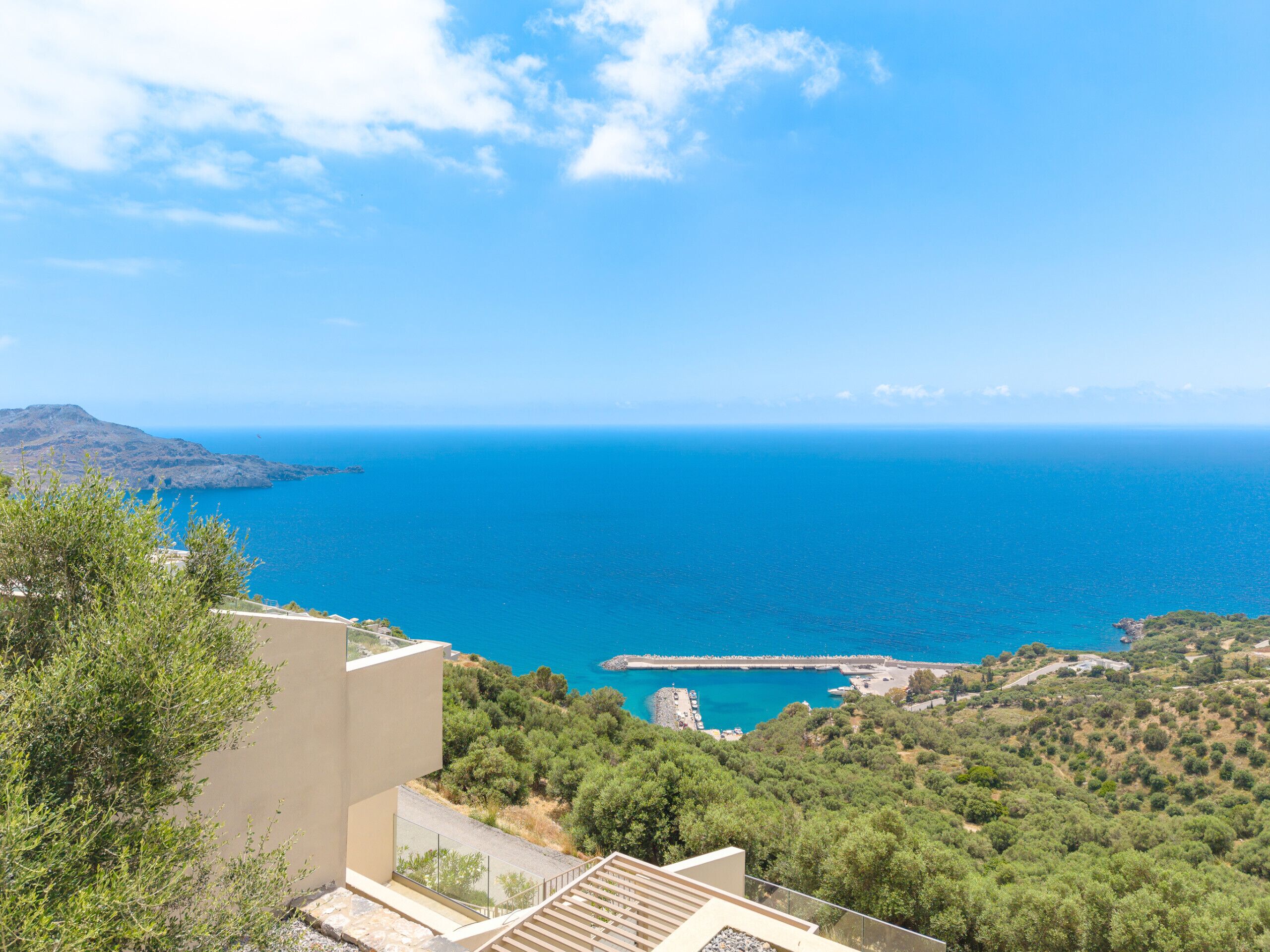 A coastal view with a clear sky, a distant coastline, and a rocky outcrop.