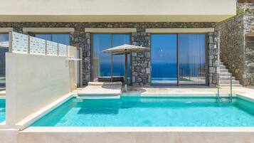 A pool area with a stone wall, a lounge chair, and a small umbrella.