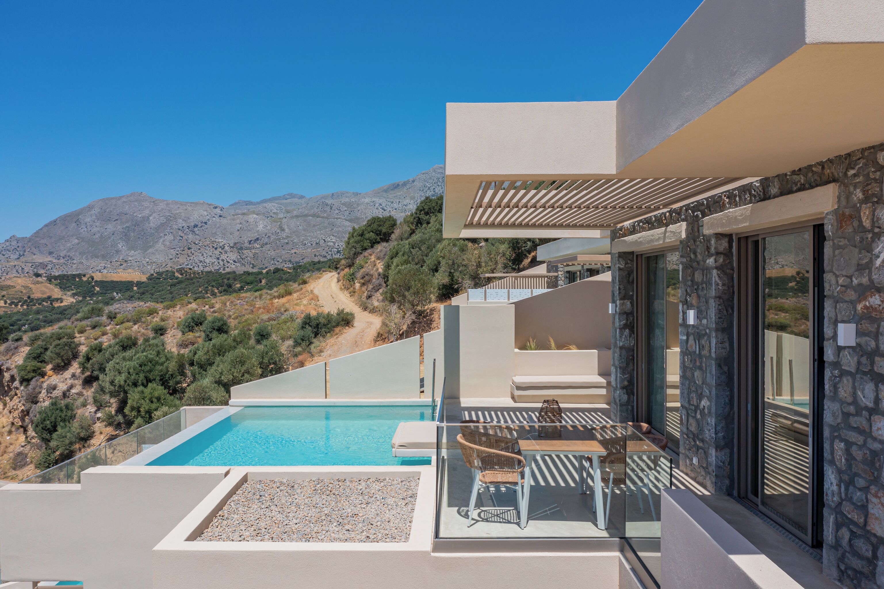A modern outdoor pool area with a clear view of the surrounding landscape and mountains.