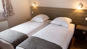 A double room with two beds, each with white bedding and a grey throw blanket. There are wall-mounted light fixtures on either side of the beds. - Hotel la grand mare  (Conches-en-Ouche)