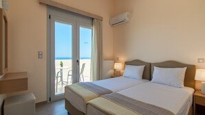 A hotel room with two beds, a balcony with a table and chairs, and an air conditioning unit. - Yanni's villas (Rethymno)