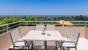 A balcony with a table and chairs, overlooking a coastal landscape. - Yanni's villas (Rethymno)