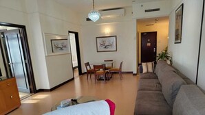 A modern living room with a sofa, a dining table with chairs, and a chandelier. - 4-bedroom apartment in marvelous City with AC, fitness room (City)