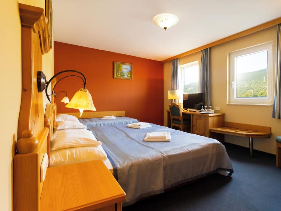 Habitación de hotel con dos camas, un escritorio, una silla, un televisor y una ventana con cortinas.