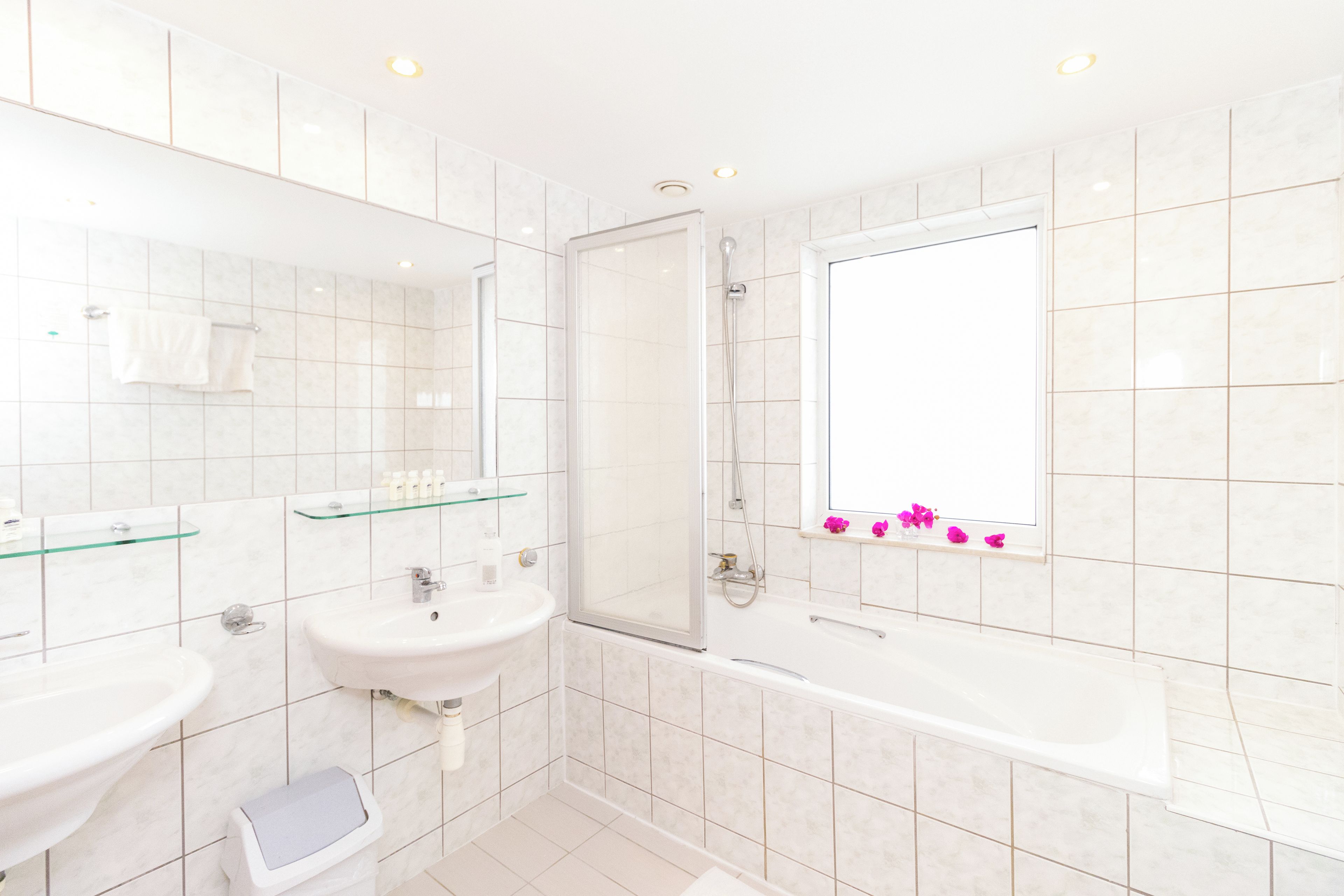 A modern bathroom with two sinks, a glass shower enclosure, and a large bathtub.