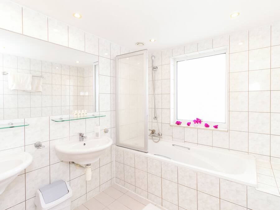 A modern bathroom with two sinks, a glass shower enclosure, and a large bathtub.