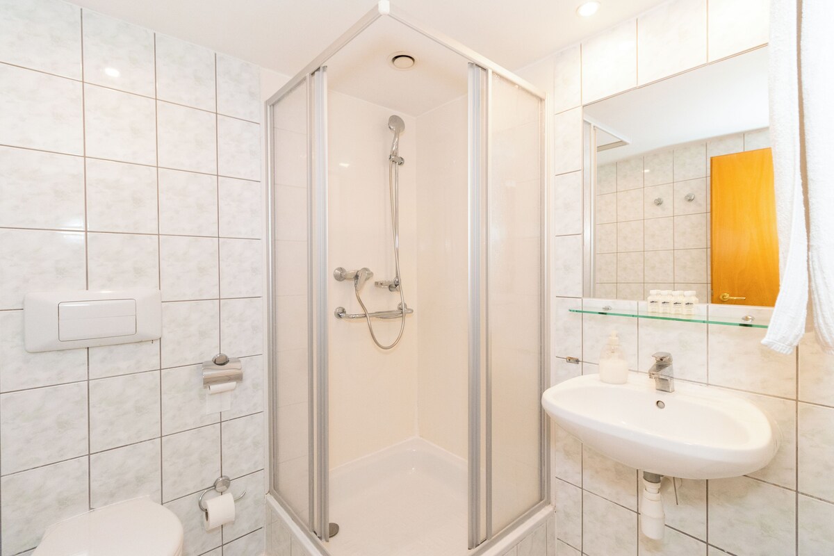 Une salle de bain moderne avec une douche à parois de verre, un lavabo blanc et des toilettes.