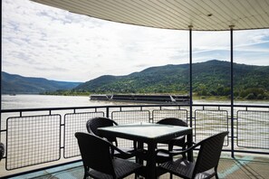 Una mesa y sillas en una terraza con vistas a un río y montañas.