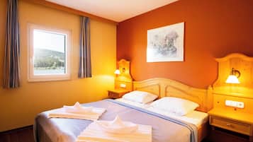 Una habitación de hotel con una cama grande, dos mesitas de noche, una ventana con cortinas y un cuadro en la pared.