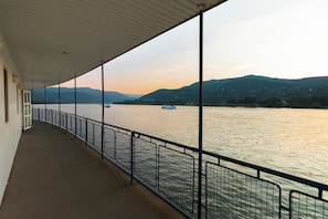 A covered walkway with a metal railing overlooking a body of water and hills. - Aquamarina Hotel Visegrád (Visegrád)