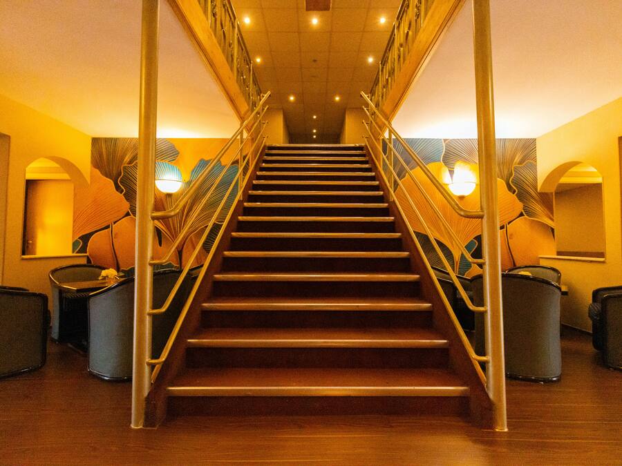 A staircase with metal railings and a wooden finish, leading to a higher floor.