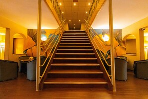 Una escalera con barandales de metal y acabados de madera, que sube a un piso superior.