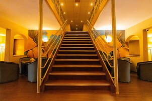 Una escalera con barandales de metal y acabados de madera, que sube a un piso superior.