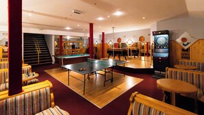 Une salle équipée de tables de ping-pong, de tables de billard et d’un jeu de fléchettes.