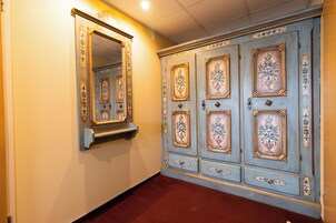 Un pasillo con un espejo grande y un panel decorativo en la pared.