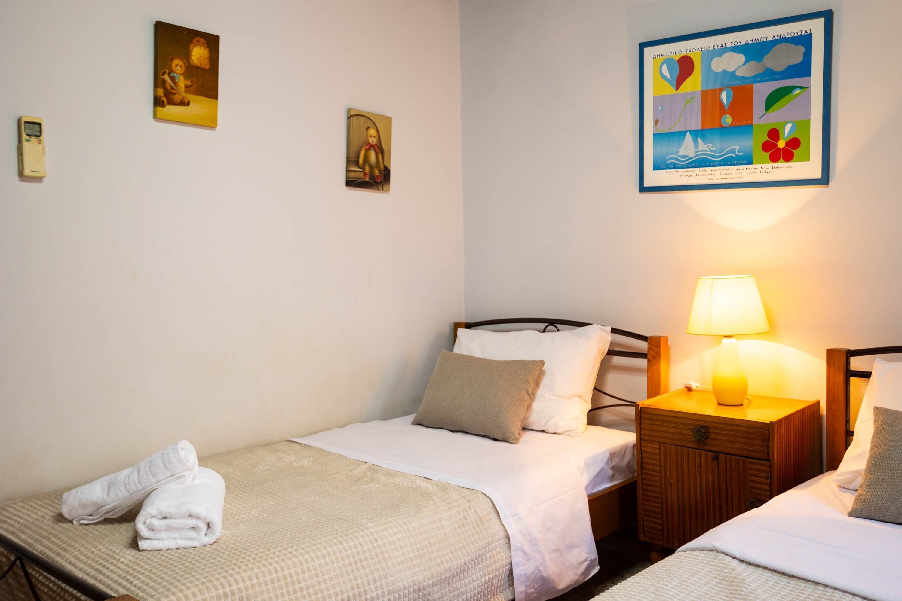 Une chambre d’hôtel avec deux lits, une table de chevet avec une lampe et des œuvres d’art accrochées au mur.