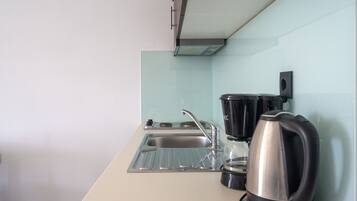 A modern kitchen with a stainless steel sink, a coffee maker, and a kettle.