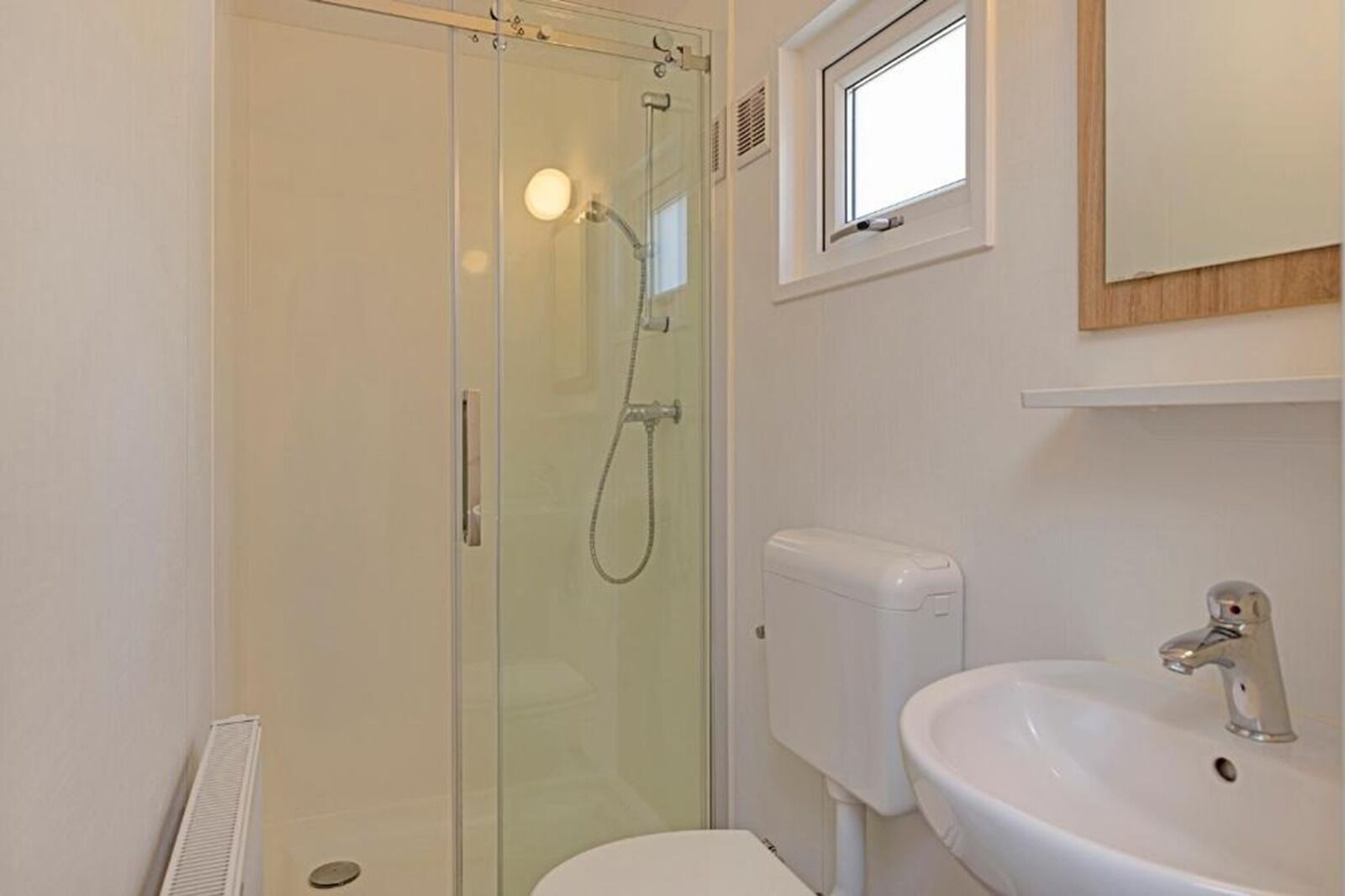 A bathroom with a glass-enclosed shower, a white sink, and a toilet.