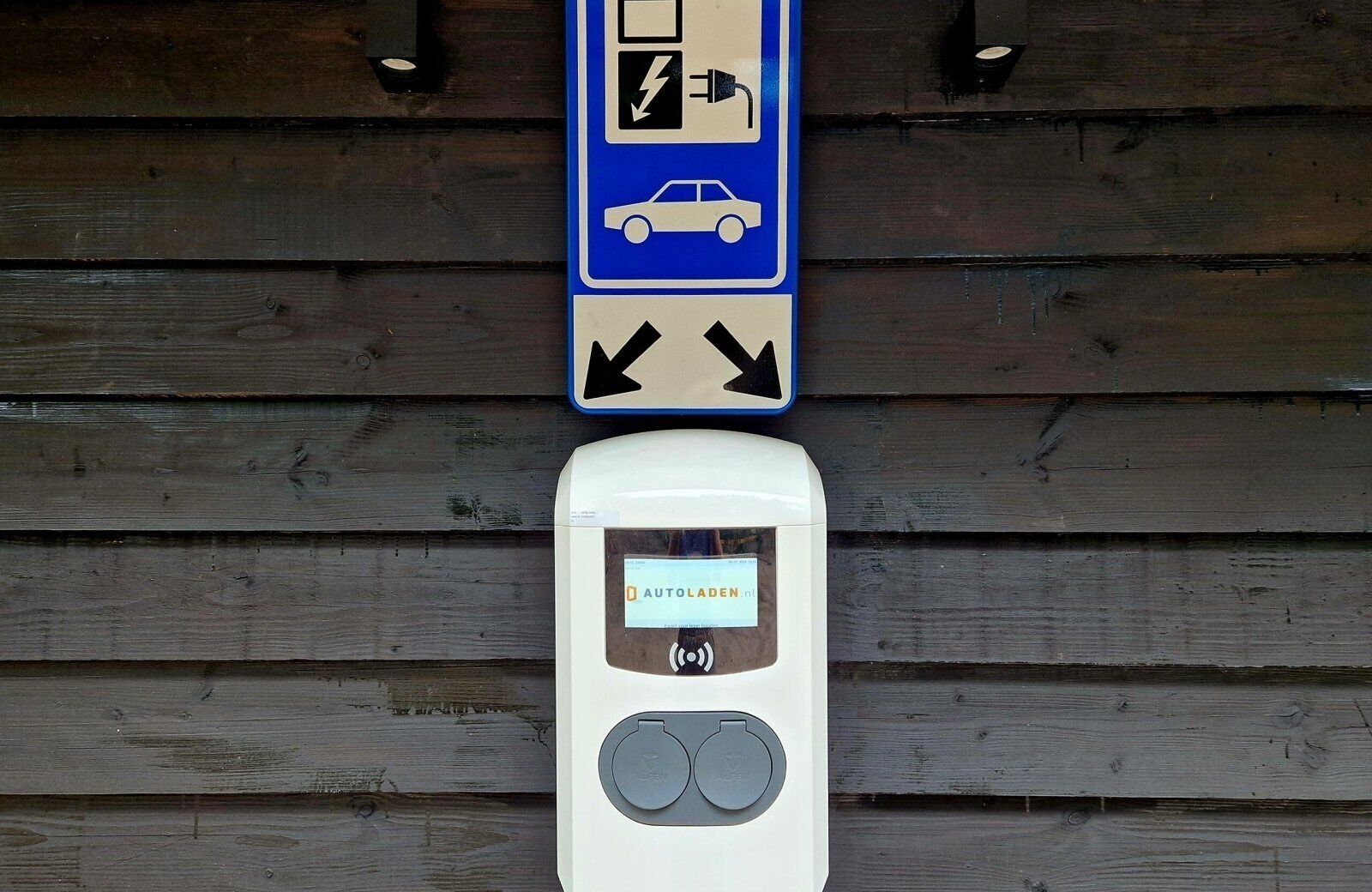 Ein Parkschild mit einem Autosymbol und einem Symbol für eine Ladestation sowie einem Bezahlsystem.