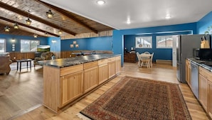 Une cuisine moderne avec des meubles en bois, un grand îlot central et un mur d’accent bleu.
