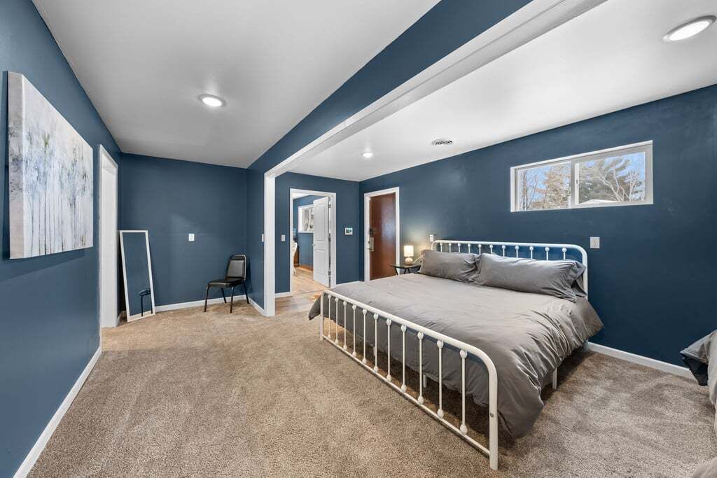 A bedroom with a bed, a chair, a desk, and a window.