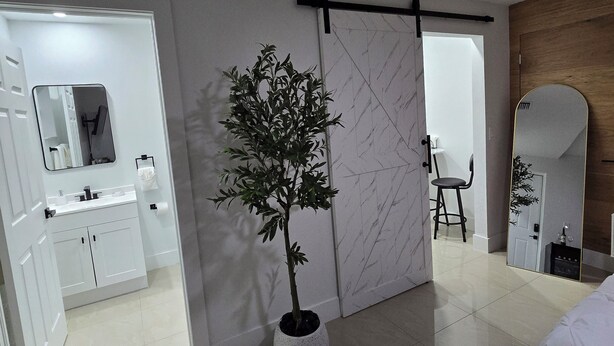 Una habitación de hotel moderna con baño, una planta en maceta, un espejo y una cama.